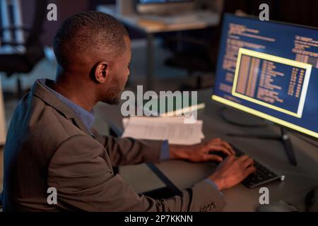 High angle view at black IT developer wearing suit and using computer while working on data security project in office Stock Photo