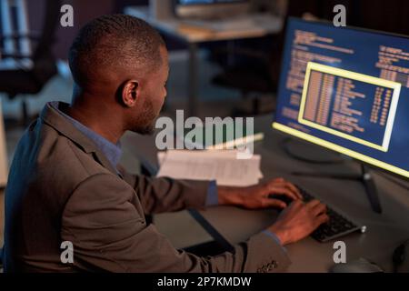 High angle view at black IT developer wearing suit and using computer while working on data security project in office Stock Photo