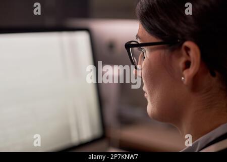 Closeup of serious businesswoman using computer while working at night in office, copy space Stock Photo