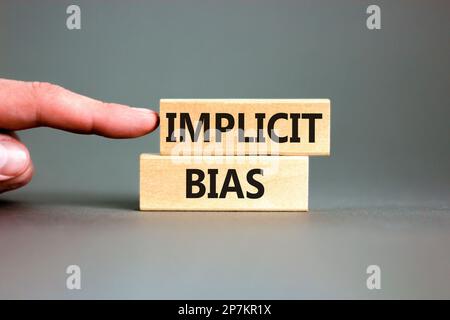 Implicit bias symbol. Concept words Implicit bias on wooden block. Beautiful grey table grey background. Businessman hand. Business psychology implici Stock Photo