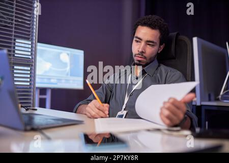 Portrait of male data scientist working with documentation at workplace in high tech office Stock Photo