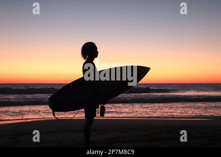 Silhouette of young male surfer on the beach at sunset Stock Photo - Alamy