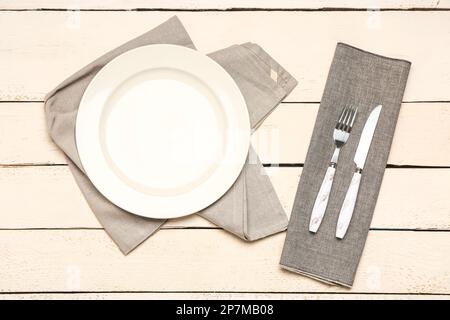 Plate, cutlery and napkins on light wooden background Stock Photo