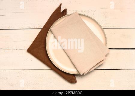 Plate with napkins on light wooden background Stock Photo