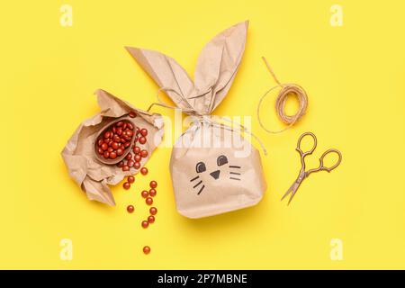 Easter bunny gift bag, candies and scissors on yellow background Stock Photo