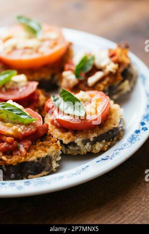 Breaded Eggplant Stacks with Tomato Sauce, Tomato Slice and Vegan Feta Stock Photo