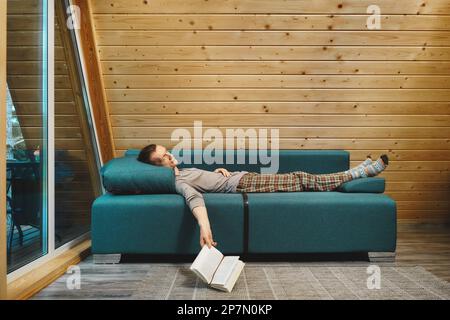 Man was reading a book in his wooden cabin in rainy day and fell asleep Stock Photo