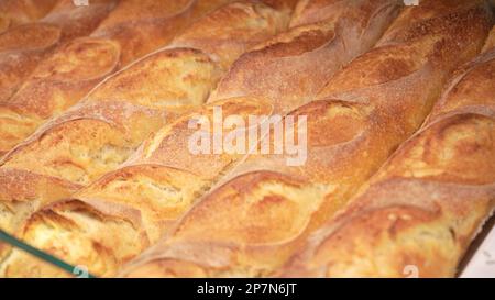 Baked loaves of bread in paper packages on the store shelf, hot crusty baguettes in local Italian bakery shops. Homemade rustic loaves of bread on mar Stock Photo