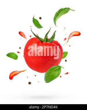 Flying tomato with splashes and basil leaves on white background. Stock Photo