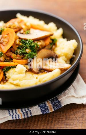 Lentil Stew with kale, carrots and mushrooms on mashed potatoes. Stock Photo