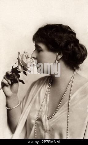 1915 c, ROMANIA : The Queen MARIA of ROMANIA ( born princesse Mary of SAXE COBURG GOTHA , 1875 - 1938 ), married with King Ferdinand ( Nando ) King of Romania ( of HOHENZALLERN SIGMARINGEN HOHENZOLLERN ) , daugther of Duke of Edinburg Alfred and the former grand Duchess Marie Alexandrovna ROMANOV Grand Duchess of Russia . In this photo sniffs the rose that was baptized in his honor ' Maria of Romania '. Photo by Julieta , Bucaresti . -  ROMANOFF  - ROYALTY - REALI - NOBILI - Nobiltà - NOBILITY - reali - regina - ROMANIA - Victoria of Great Britain England - regina VITTORIA d' Inghilterra - BEL Stock Photo