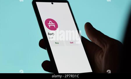 An investor's analyzing the Amp ( AMP ) coin on screen. A phone shows the crypto's prices to invest in amp token. Stock Photo