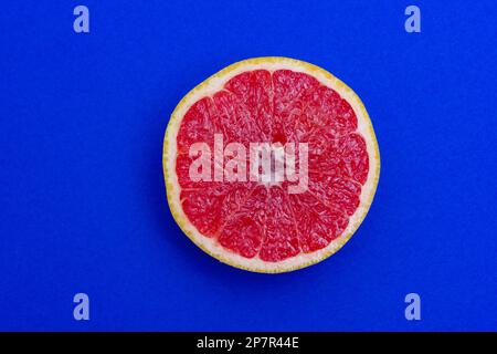 Sliced side of a grapefruit with red pulp isolated on a blue background Stock Photo