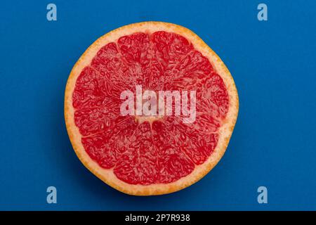 Sliced side of a grapefruit with red pulp isolated on a blue background Stock Photo