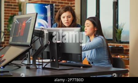 Diverse team of employees analyzing project component on multi screens, using engineering software on pc. Creative designers developing art on computer, discussing about 3D technology. Stock Photo