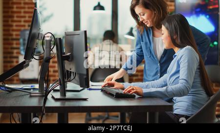 Female app developers working on software production with multiple displays, using computers interface to develop new professional content. Creative agency workers creating 3d scene project. Stock Photo