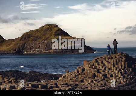 Father and daughter standing on stone formation at the giant's causeway and looking at the sea Stock Photo