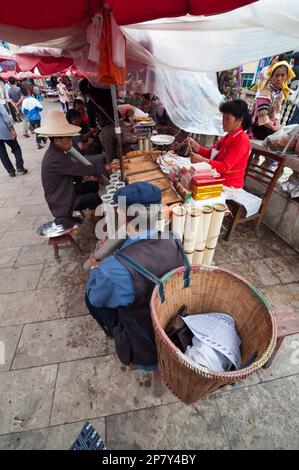 A man smoking from a traditional large long stem bamboo pipe at a market tobacco stand in Jianshui Yunnan Province China Stock Photo