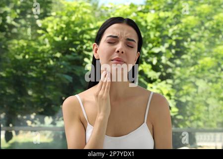 Young woman doing thyroid self examination near window Stock Photo