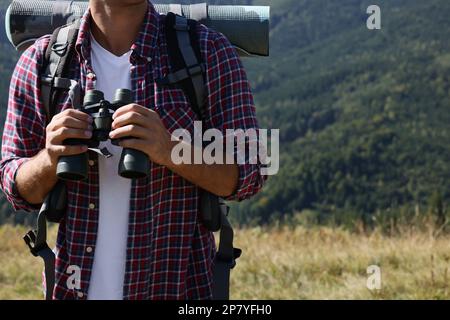 Tourist with hiking equipment and binoculars in mountains, closeup Stock Photo