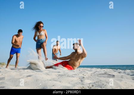 Group of friends playing football on beach Stock Photo