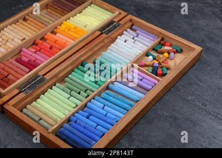 Set of colorful pastels in wooden box on grey stone table, closeup. Drawing materials Stock Photo