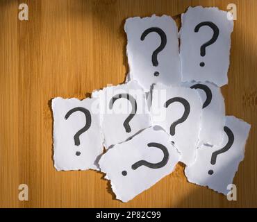 Heap of white papers with question mark. Top view. Confusion or indecision concept. Stock Photo