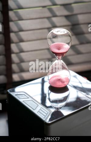 Sand running or flowing down of an hourglass measuring the passing of time. Close up view, copy space. Stock Photo