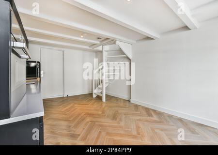 an empty living room with wood flooring and white walls in the room is well lit by the light coming through the window Stock Photo