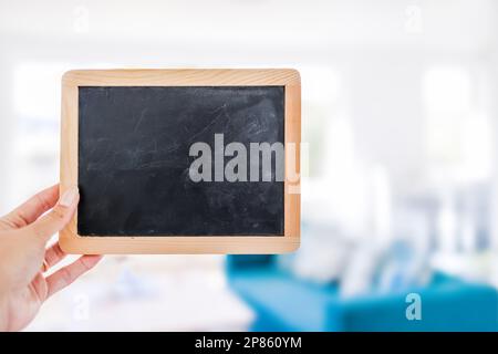 hand holding small blackboard with blank copy space in front of stylish living room background, space for your text Stock Photo