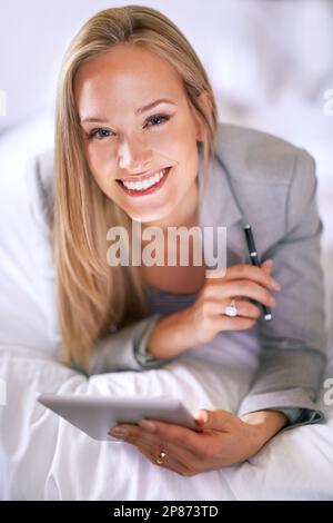 My compact companion. A young businesswoman using a digital tablet in a bedroom. Stock Photo
