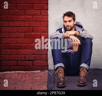 Coffee is my winter warmer. a stylish young man in winter wear holding a hot drink. Stock Photo