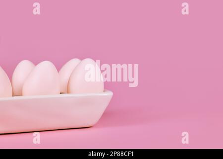 Simple one colored Easter eggs in egg tray on pink background with copy space Stock Photo