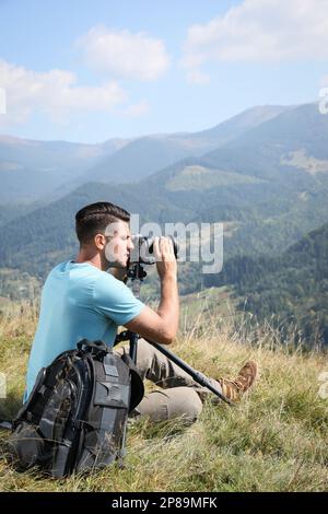 Professional photographer taking picture with modern camera in mountains Stock Photo
