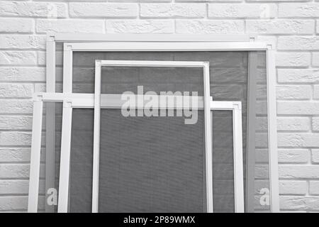 Set of window screens near white brick wall, closeup Stock Photo - Alamy