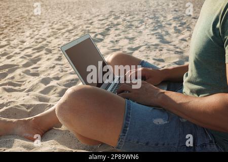 Man working with laptop on beach, closeup Stock Photo