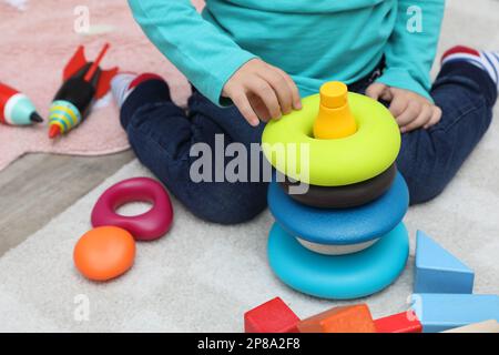 Little child playing with stacking toy on carpet, closeup Stock Photo