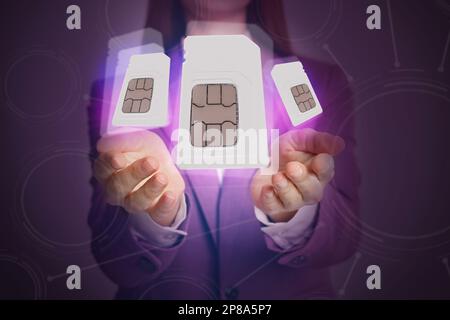 Woman demonstrating SIM cards of different sizes on color background, closeup Stock Photo