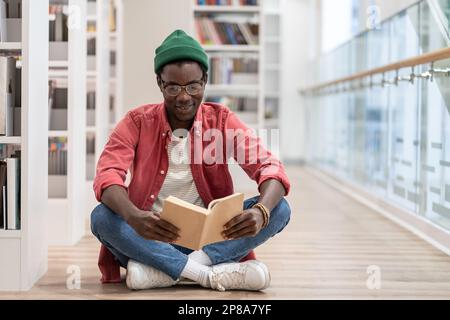 Focused African American guy preparing materials for upcoming lecture reading book in university Stock Photo