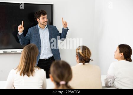 Young male tutor teaching students in college classroom Stock Photo
