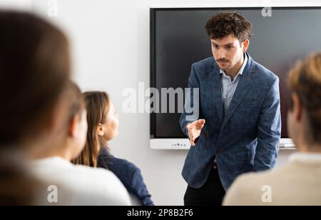 Young male teacher giving lecture to group of student Stock Photo
