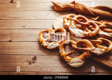 Fresh baked homemade German pretzel with sea salt on wooden table. Classic beer snack, baked pastry. Stock Photo
