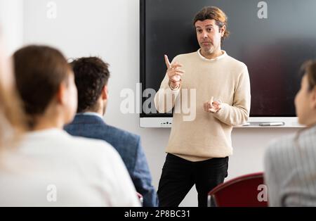 Experienced male teacher giving lecture to group of student Stock Photo