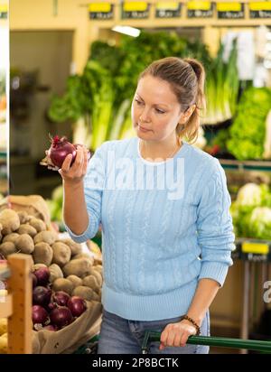 woman buy large onion in supermarket Stock Photo