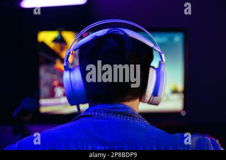 Young man getting into the vibrant world of online gaming. Computer gamer immersing himself in a first-person shooter gameplay, delivering electrifyin Stock Photo