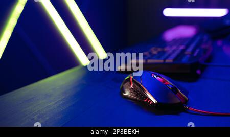 Gaming setup with a computer mouse placed on a table next to a gamer's PC. Perfect for gaming enthusiasts, the station is filled with vibrant light an Stock Photo