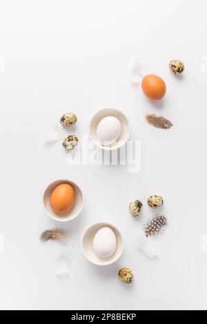 Different eggs with feathers for Easter on white background Stock Photo