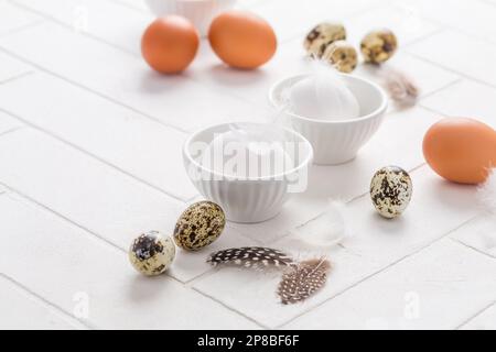 Different eggs with feathers for Easter on white background Stock Photo