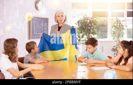 Female teacher showing swedish flag to kids in geography class Stock Photo