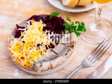 Sliced herring with grated beetroot and cheese served on table Stock Photo